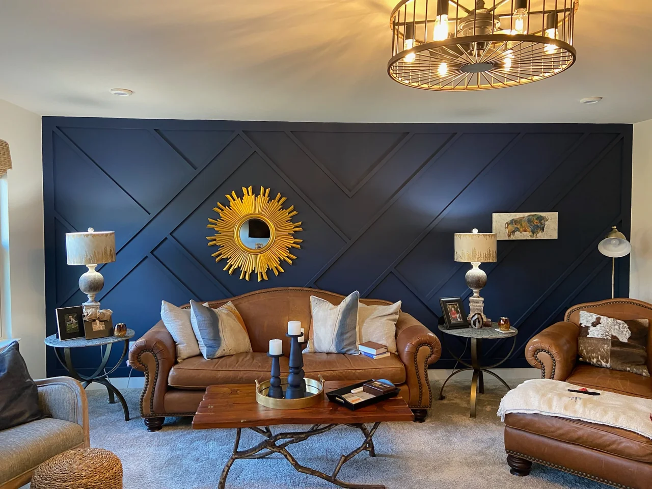 Navy geometric trim wall with a gold sunburst mirror and leather seating.