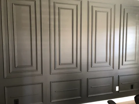Layered rectangular molding adds depth to a gray office wall.