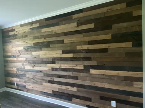 Horizontal boards in varied wood tones cover a bedroom feature wall.