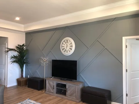 A gray geometric wall creates a backdrop for a television and low console.