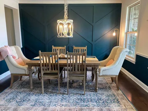 Angled trim adds a large geometric pattern to a deep teal dining-room wall.