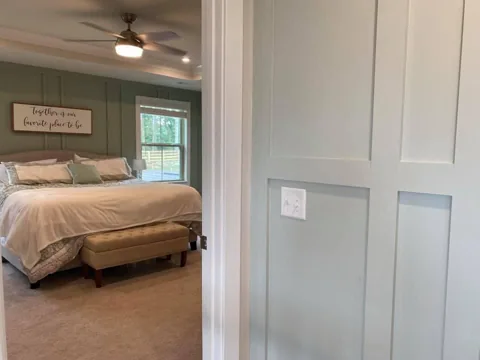 Picture-frame molding continues around a doorway beside a bedroom.