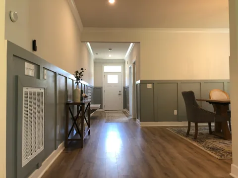 Gray lower wall panels line an entry hall with wood flooring.