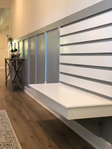 A white entry bench sits against horizontal boards and gray wall paneling.