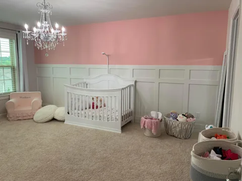 White lower wall panels contrast with a soft pink nursery wall.