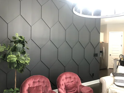 Charcoal hexagonal trim forms a feature wall beside pink chairs.