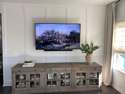 White wall panels add a subtle pattern behind a television and console.