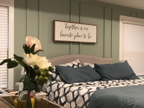 Gray rectangular molding frames a bed beneath wall art.