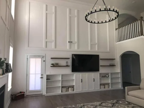 White panels and shelving define a tall living-room television wall.