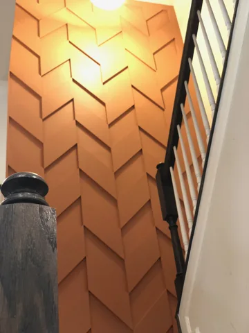A warm-colored geometric trim wall follows a staircase.