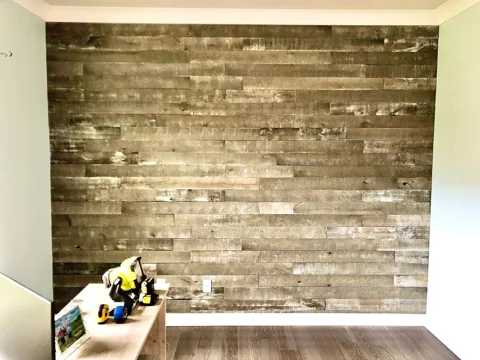 Mixed wood boards form a textured wall behind a desk.