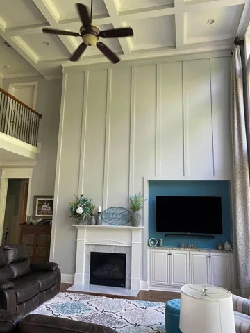 Tall sage-green panels rise above a living-room television and fireplace.