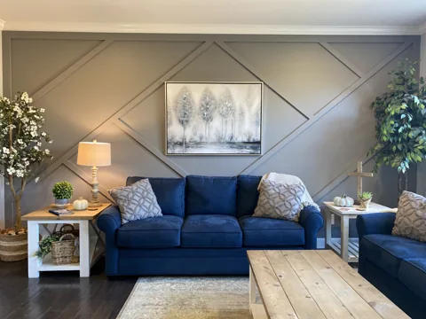 Broad diagonal trim creates a diamond pattern behind a blue sofa.