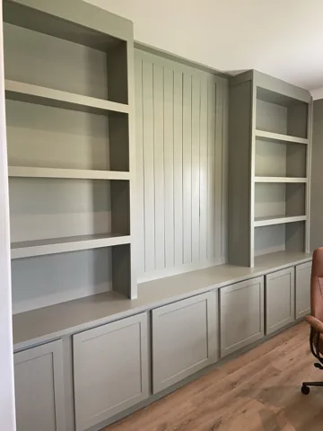 Open shelving and lower paneled cabinets are set beside a vertical feature panel.