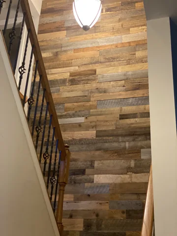Horizontal wood planks follow the wall beside a stair railing.