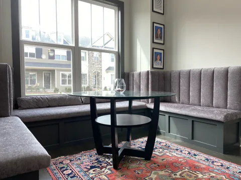 A corner bench with a tall upholstered back wraps around a dining table.