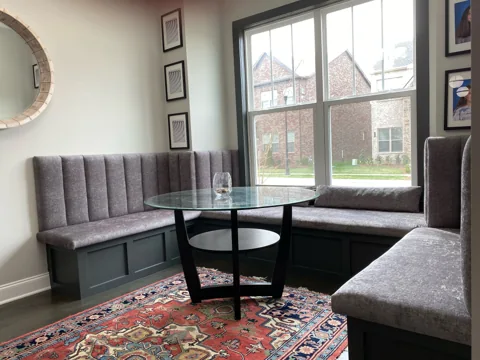 An upholstered banquette and round table create a window-side dining area.