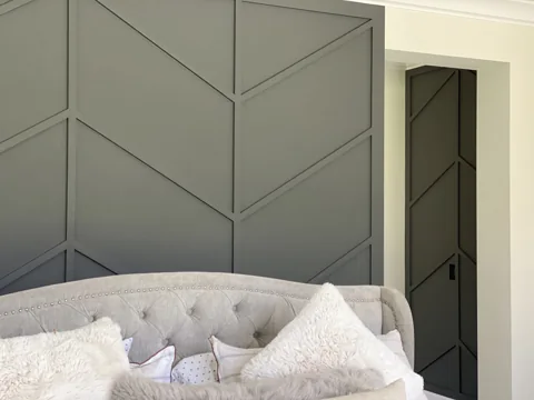 A close view of green angular wall trim beside a bed and doorway.