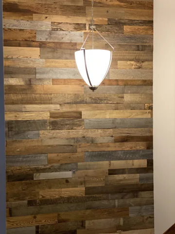 Varied horizontal wood planks create a stairwell backdrop for a hanging light.