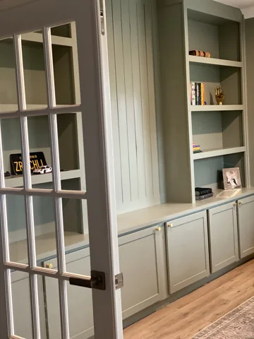 Tall light-colored bookshelves and cabinets sit behind glass-paneled doors.