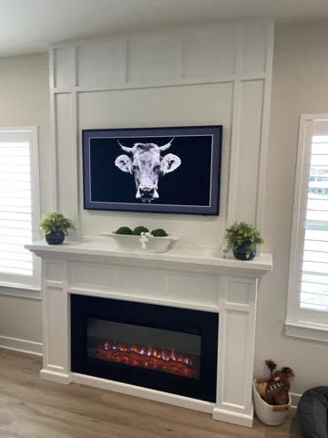 White trim panels frame a television and fireplace beneath a wood-toned ceiling fan.