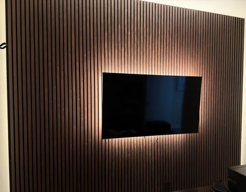 Natural wood-colored vertical slats form a television wall.