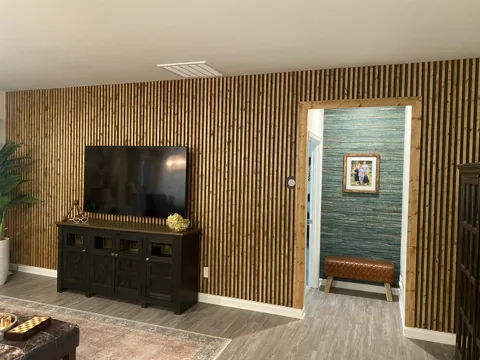 A wood-slat television wall continues beside a doorway and dark lower console.