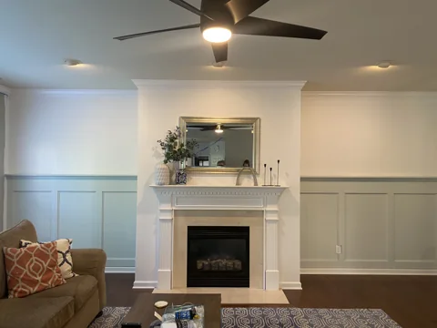 White lower wall panels lead to a fireplace with a detailed white surround.