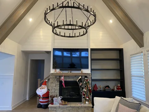 A high living-room wall has white trim and shelving around a fireplace and television.